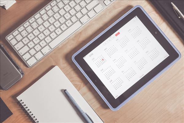 A tablet displays a calendar on a desk